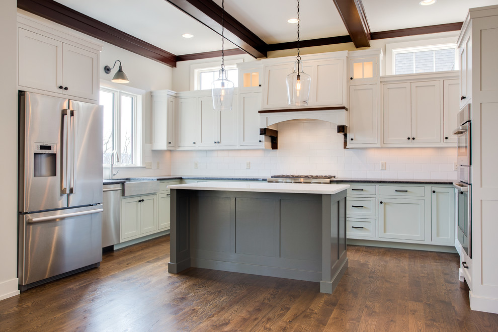 Example of an arts and crafts medium tone wood floor eat-in kitchen design in Other with a farmhouse sink, shaker cabinets, gray cabinets, granite countertops, white backsplash, subway tile backsplash, stainless steel appliances and an island