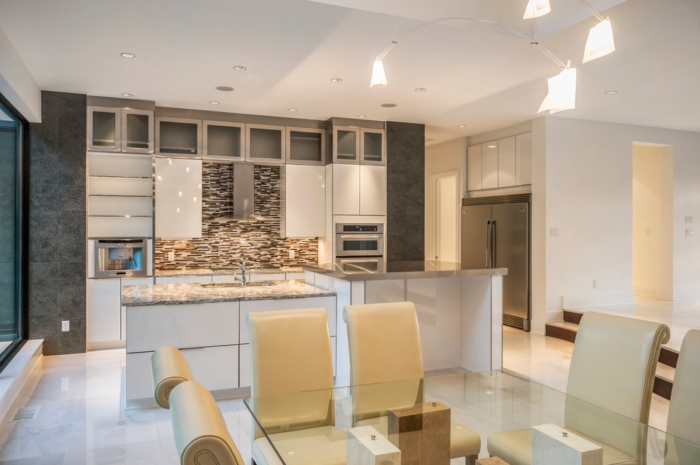 Example of a mid-sized minimalist single-wall marble floor open concept kitchen design in Cincinnati with a double-bowl sink, flat-panel cabinets, white cabinets, granite countertops, brown backsplash, mosaic tile backsplash, stainless steel appliances and an island