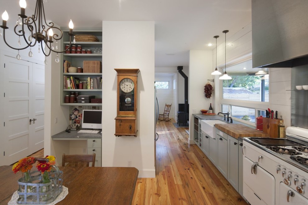 Cette image montre une cuisine américaine rustique en L avec un placard avec porte à panneau encastré, des portes de placard grises, une crédence métallisée, une crédence en dalle métallique et un électroménager blanc.