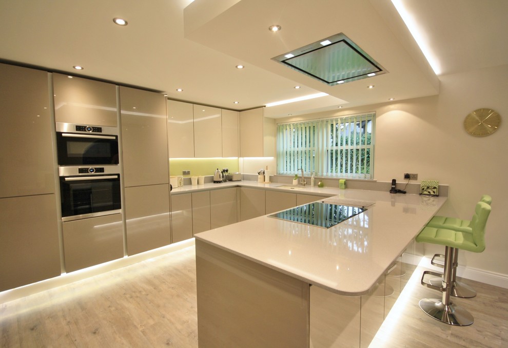This is an example of a large contemporary u-shaped kitchen/diner in Essex with a single-bowl sink, flat-panel cabinets, grey cabinets, quartz worktops, stainless steel appliances and no island.