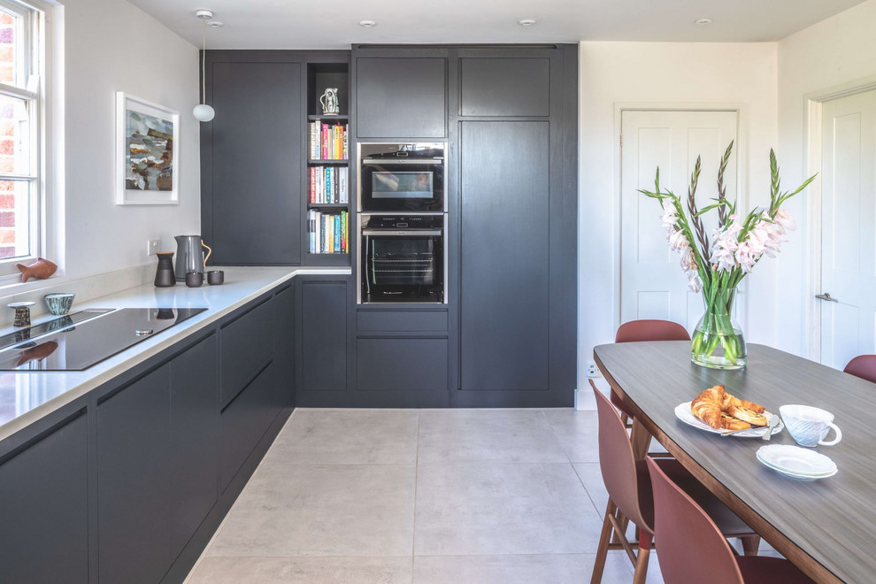Inspiration for a medium sized contemporary l-shaped kitchen/diner in Gloucestershire with a built-in sink, flat-panel cabinets, blue cabinets, quartz worktops, white splashback, black appliances, ceramic flooring, no island, white floors and white worktops.