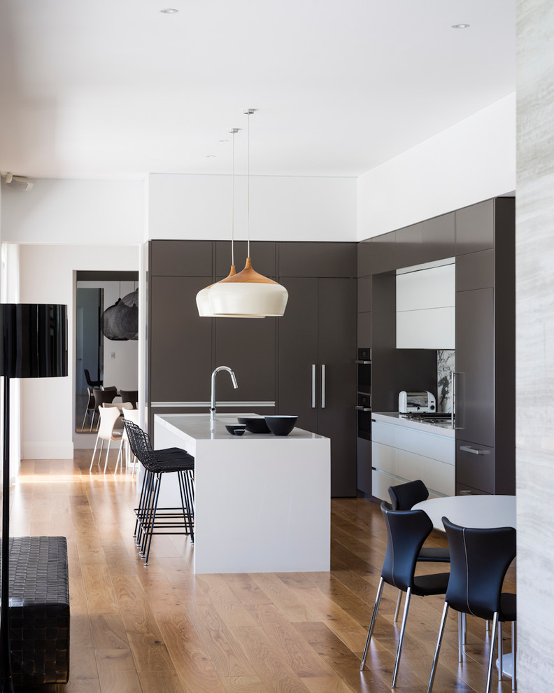 Esempio di una cucina minimal con ante lisce, paraspruzzi grigio, elettrodomestici da incasso, pavimento in legno massello medio e pavimento marrone