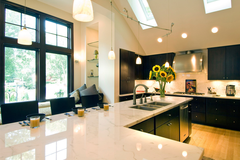 Inspiration for a large contemporary limestone floor eat-in kitchen remodel in Indianapolis with a triple-bowl sink, flat-panel cabinets, black cabinets, quartzite countertops, white backsplash, stone slab backsplash, stainless steel appliances and an island