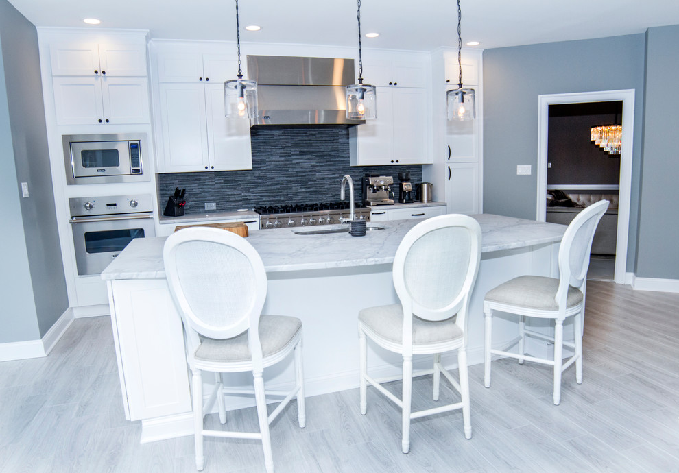 Bild på ett mellanstort funkis linjärt kök, med en undermonterad diskho, skåp i shakerstil, vita skåp, marmorbänkskiva, vitt stänkskydd, stänkskydd i stickkakel, rostfria vitvaror, ljust trägolv och en köksö