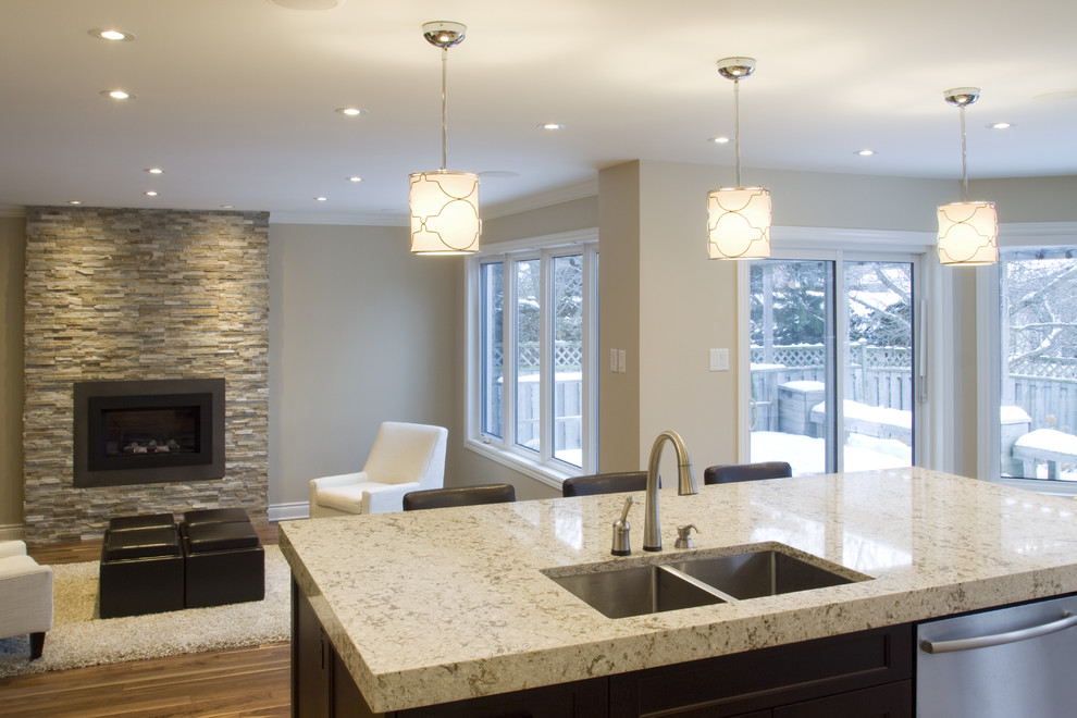 Open concept kitchen - large contemporary l-shaped medium tone wood floor open concept kitchen idea in Ottawa with a double-bowl sink, shaker cabinets, white cabinets, quartz countertops, stainless steel appliances and an island
