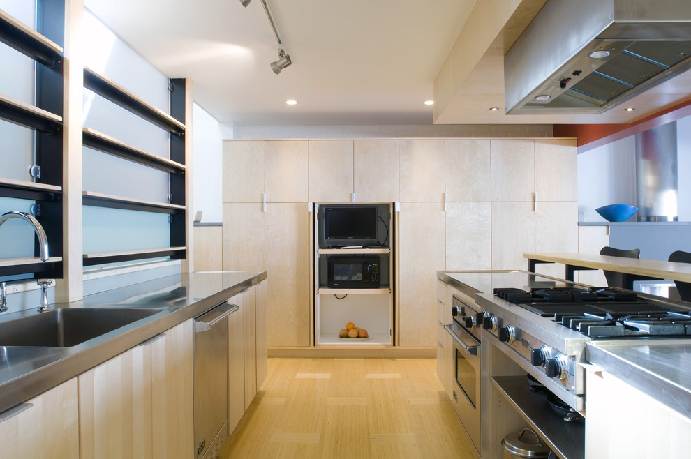 Idéer för att renovera ett funkis kök, med rostfria vitvaror, bänkskiva i rostfritt stål, en integrerad diskho, släta luckor och skåp i ljust trä