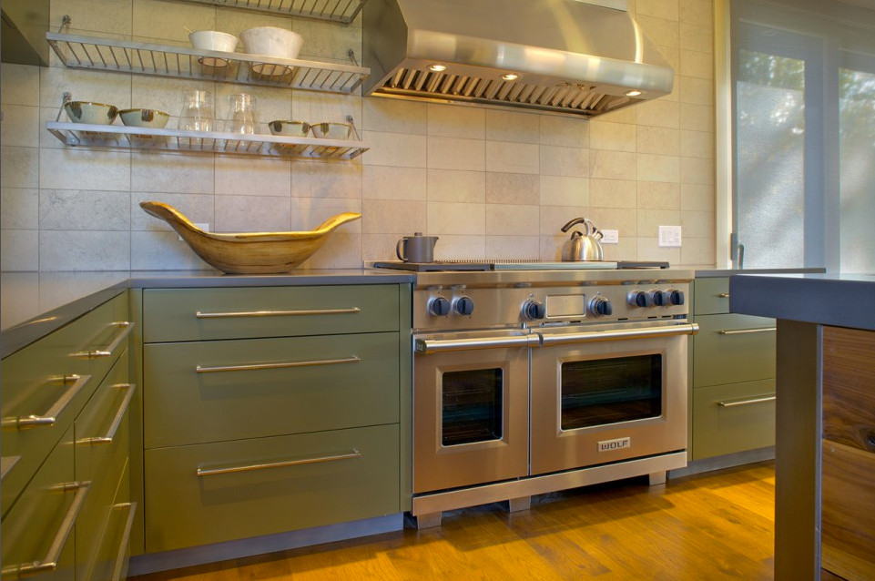 Enclosed kitchen - mid-sized 1960s l-shaped medium tone wood floor enclosed kitchen idea in Other with an undermount sink, flat-panel cabinets, green cabinets, quartz countertops, beige backsplash, stone tile backsplash, stainless steel appliances and an island