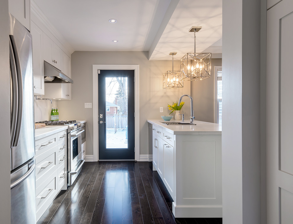 Inspiration for a small transitional galley dark wood floor eat-in kitchen remodel in Toronto with an undermount sink, shaker cabinets, white cabinets, quartz countertops, white backsplash, stone slab backsplash, stainless steel appliances and an island