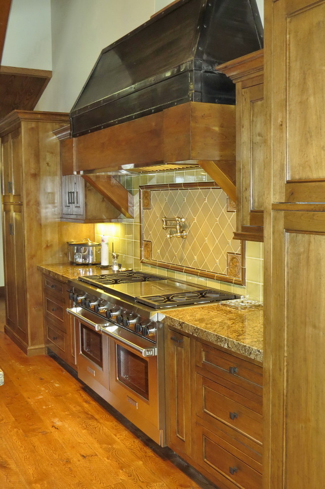 Bild på ett stort lantligt kök, med en undermonterad diskho, luckor med upphöjd panel, skåp i mellenmörkt trä, granitbänkskiva, stänkskydd i stenkakel, integrerade vitvaror, mellanmörkt trägolv och flera köksöar