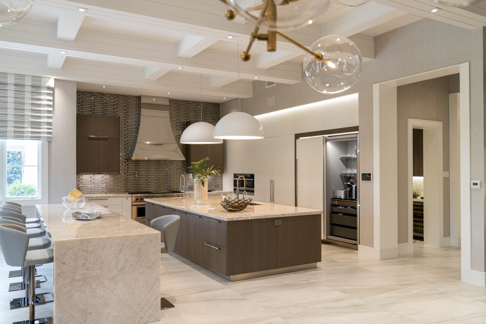This is an example of an expansive traditional l-shaped enclosed kitchen in Miami with a submerged sink, flat-panel cabinets, medium wood cabinets, quartz worktops, metallic splashback, glass tiled splashback, integrated appliances, porcelain flooring, multiple islands, grey floors and beige worktops.