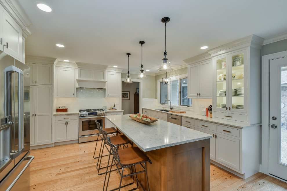 Klassisk inredning av ett mellanstort vit vitt kök, med skåp i shakerstil, vita skåp, bänkskiva i kvarts, vitt stänkskydd, stänkskydd i keramik, ljust trägolv, en köksö och gult golv