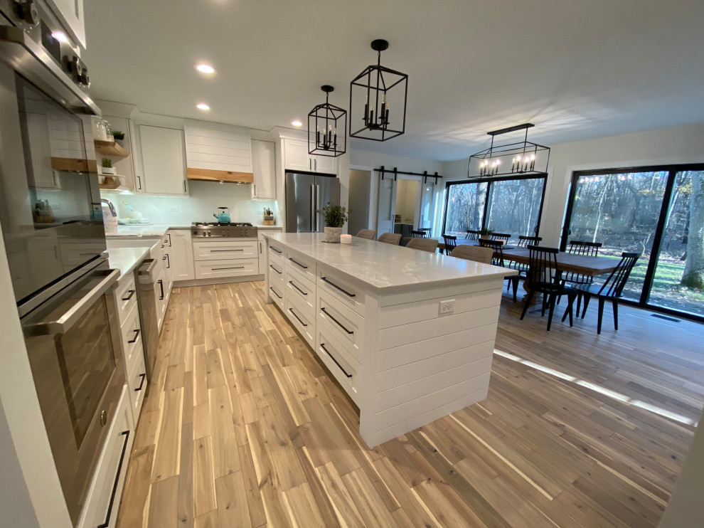 Inspiration for a large cottage galley light wood floor and beige floor open concept kitchen remodel in Chicago with a farmhouse sink, shaker cabinets, white cabinets, quartz countertops, white backsplash, porcelain backsplash, stainless steel appliances, an island and gray countertops