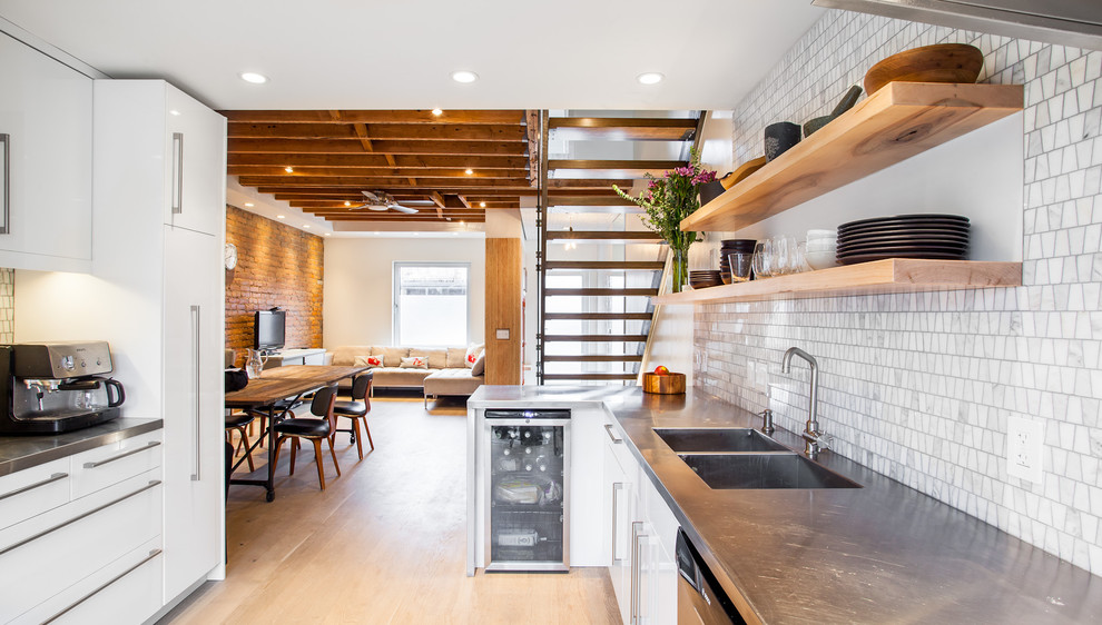 Moderne Küche mit integriertem Waschbecken, Edelstahl-Arbeitsplatte, flächenbündigen Schrankfronten, weißen Schränken, Küchenrückwand in Weiß und Rückwand aus Steinfliesen in Toronto