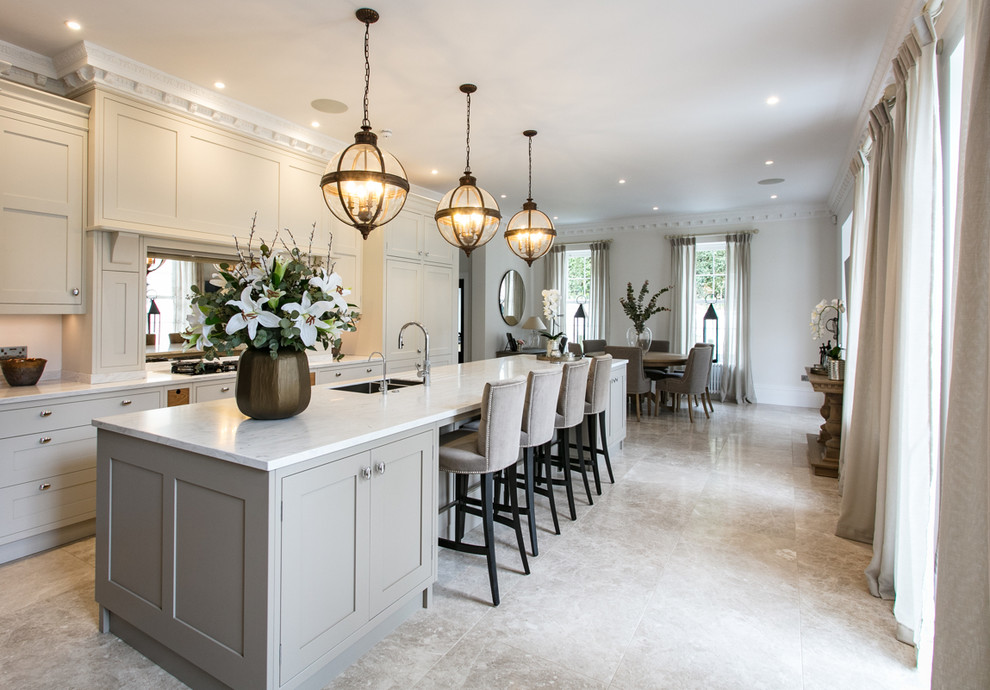 Large traditional single-wall kitchen/diner in Surrey with a built-in sink, shaker cabinets, grey cabinets, composite countertops, metallic splashback, glass sheet splashback, stainless steel appliances, marble flooring, an island, grey floors and white worktops.