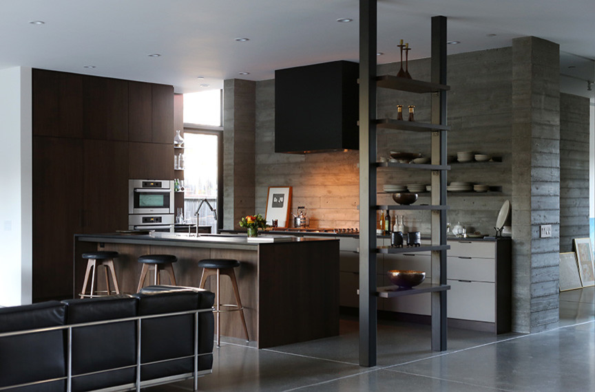 Cette image montre une cuisine ouverte minimaliste en L et bois foncé de taille moyenne avec un placard à porte plane, un électroménager en acier inoxydable, sol en béton ciré et îlot.