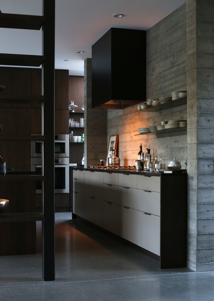 Inspiration for a transitional u-shaped concrete floor open concept kitchen remodel in San Francisco with an undermount sink, flat-panel cabinets, dark wood cabinets and paneled appliances