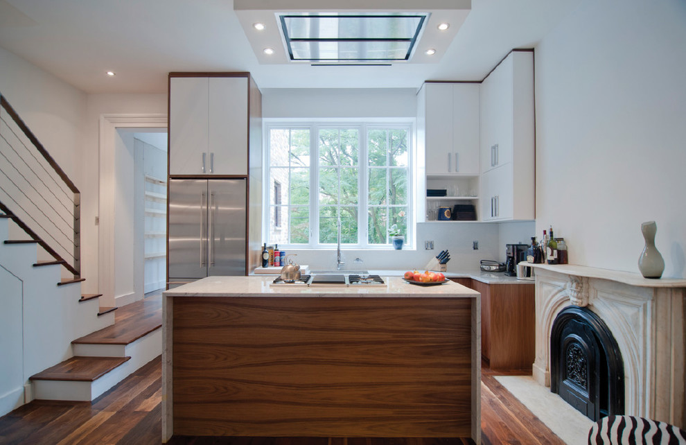 Exemple d'une cuisine ouverte parallèle tendance avec un placard à porte plane, des portes de placard blanches et un électroménager en acier inoxydable.