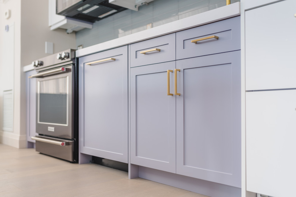 Modern inredning av ett litet vit linjärt vitt kök och matrum, med en undermonterad diskho, släta luckor, grå skåp, bänkskiva i kvarts, grått stänkskydd, stänkskydd i glaskakel, svarta vitvaror, ljust trägolv, en köksö och grått golv