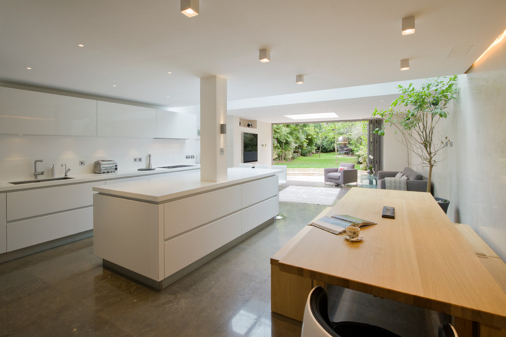 Design ideas for a large contemporary kitchen in London with an island, flat-panel cabinets, white cabinets, composite countertops, white splashback, stone slab splashback, stainless steel appliances, a submerged sink and limestone flooring.
