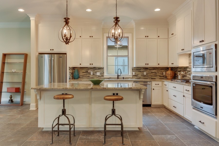 Elegant l-shaped eat-in kitchen photo in New Orleans with an undermount sink, recessed-panel cabinets, white cabinets, granite countertops, multicolored backsplash, matchstick tile backsplash and an island