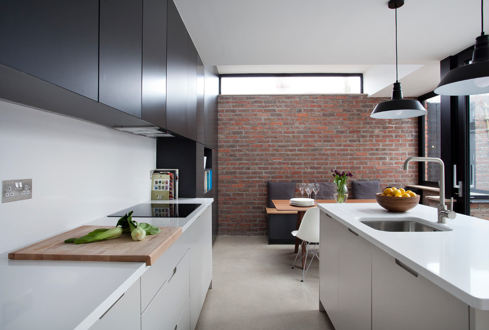 Источник вдохновения для домашнего уюта: кухня в современном стиле с обеденным столом, врезной мойкой, плоскими фасадами, белым фартуком, бетонным полом, островом и черно-белыми фасадами