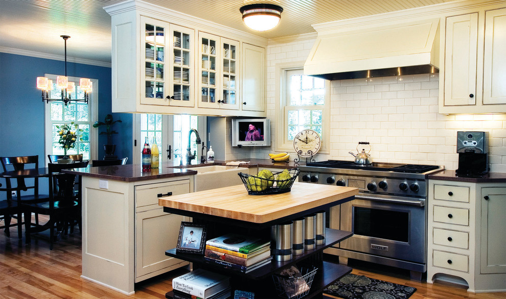 Example of a cottage eat-in kitchen design in Minneapolis with a farmhouse sink, stainless steel appliances, wood countertops, beaded inset cabinets, beige cabinets, white backsplash and subway tile backsplash