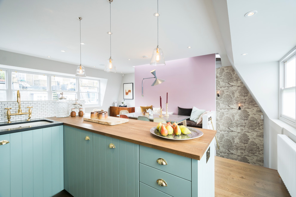 This is an example of a medium sized traditional kitchen in London with light hardwood flooring.