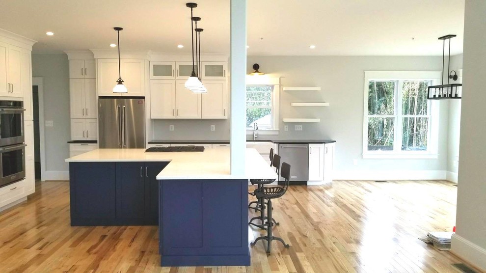 Example of a huge beach style l-shaped light wood floor and brown floor eat-in kitchen design in Baltimore with a single-bowl sink, shaker cabinets, white cabinets, granite countertops, stainless steel appliances, an island and white countertops