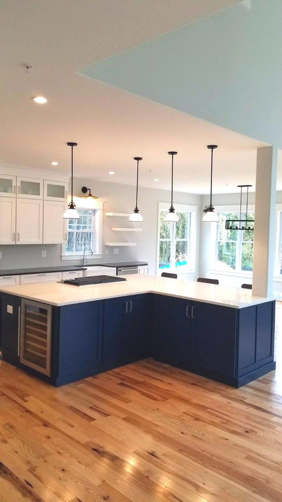 Inspiration for an expansive beach style l-shaped kitchen/diner in Baltimore with a single-bowl sink, shaker cabinets, white cabinets, granite worktops, stainless steel appliances, light hardwood flooring, an island, brown floors and white worktops.