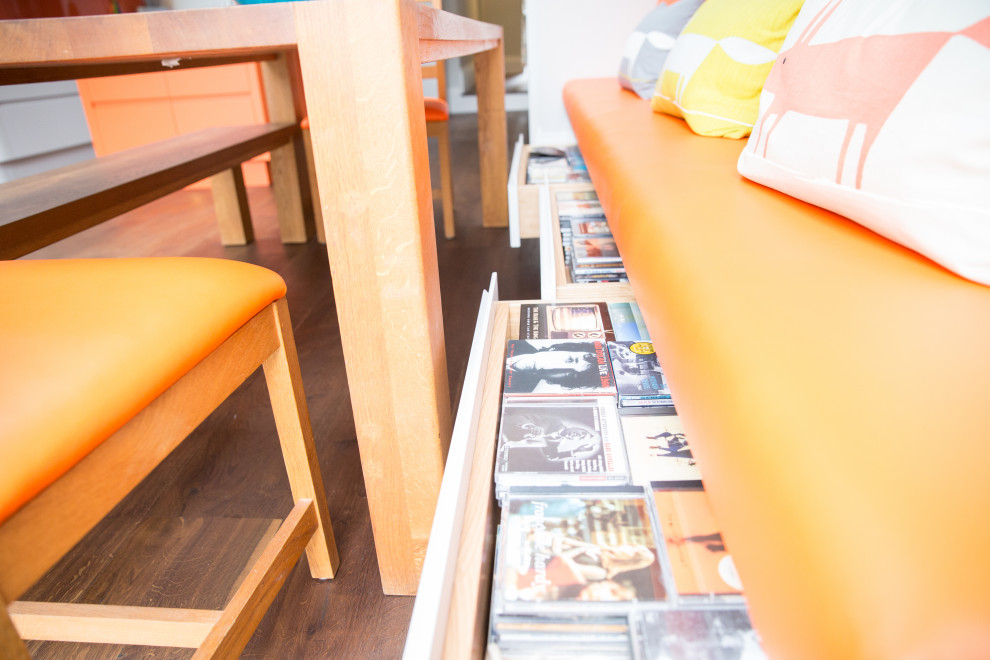 Esempio di una cucina moderna di medie dimensioni con lavello a vasca singola, ante lisce, ante arancioni, top in superficie solida, paraspruzzi arancione, paraspruzzi con piastrelle di vetro, parquet scuro, pavimento marrone e top bianco