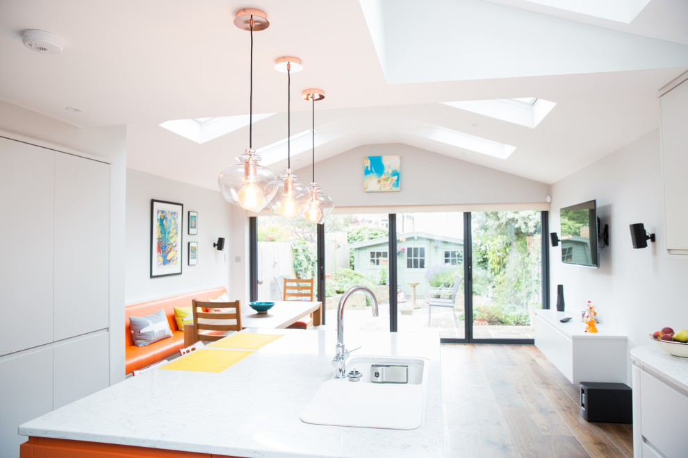 Esempio di una cucina moderna di medie dimensioni con lavello a vasca singola, ante lisce, ante arancioni, top in superficie solida, paraspruzzi arancione, paraspruzzi con piastrelle di vetro, parquet scuro, pavimento marrone e top bianco