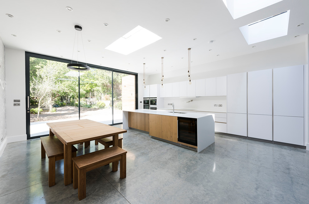 Immagine di una grande cucina minimal con lavello a doppia vasca, ante bianche, top in superficie solida, elettrodomestici in acciaio inossidabile e pavimento in cemento