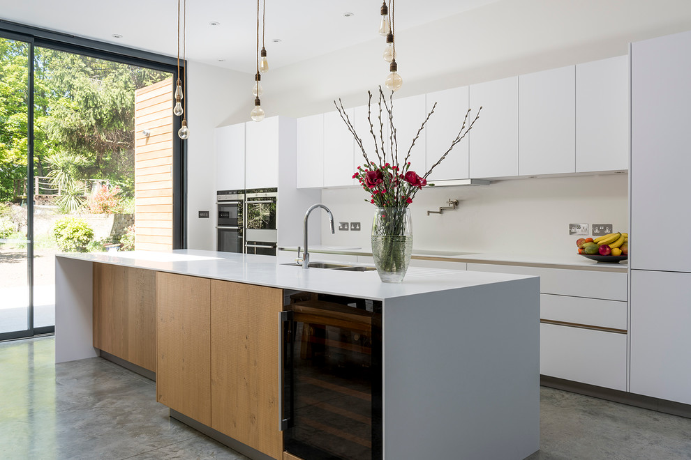 Modern inredning av ett stort kök och matrum, med en dubbel diskho, vita skåp, bänkskiva i koppar, rostfria vitvaror, betonggolv och en köksö