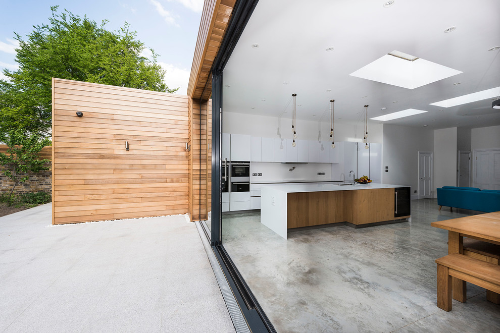 Idéer för ett stort modernt kök och matrum, med en dubbel diskho, vita skåp, bänkskiva i koppar, rostfria vitvaror, betonggolv och en köksö