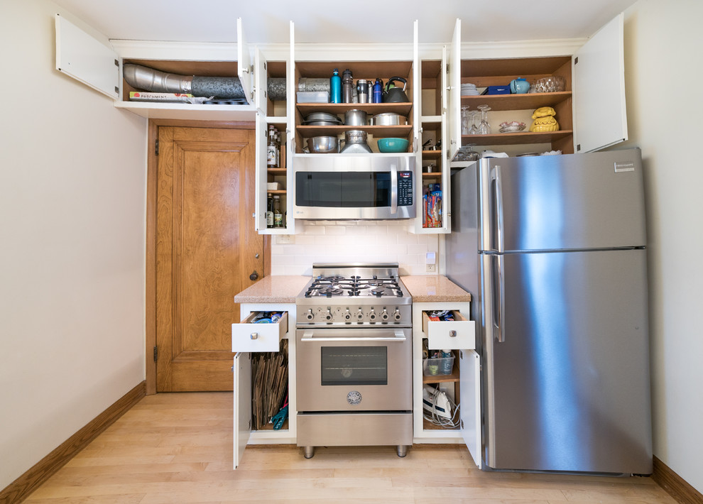 Enclosed kitchen - small craftsman galley light wood floor enclosed kitchen idea in Minneapolis with a double-bowl sink, flat-panel cabinets, white cabinets, laminate countertops, white backsplash, subway tile backsplash, stainless steel appliances and no island