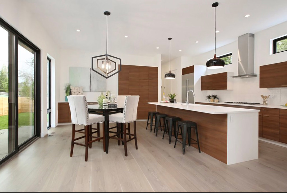 Inspiration for a medium sized contemporary u-shaped kitchen/diner in Denver with a submerged sink, flat-panel cabinets, medium wood cabinets, engineered stone countertops, white splashback, stainless steel appliances, light hardwood flooring and an island.