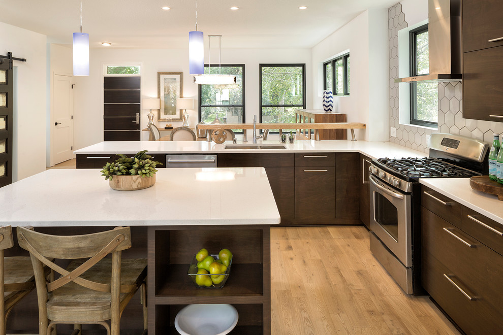 Inspiration for a medium sized contemporary u-shaped open plan kitchen in Minneapolis with a double-bowl sink, flat-panel cabinets, dark wood cabinets, engineered stone countertops, white splashback, ceramic splashback, stainless steel appliances, light hardwood flooring, an island and beige floors.