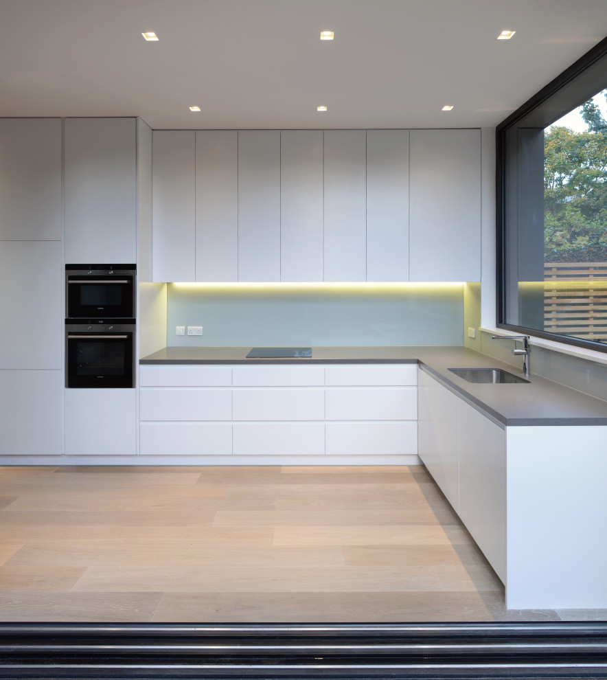 Idées déco pour une cuisine ouverte moderne en L de taille moyenne avec un placard à porte plane, des portes de placard blanches et un plan de travail en surface solide.