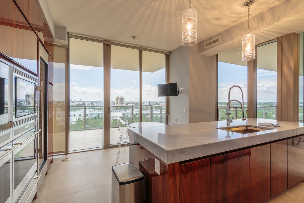 Photo of a large contemporary galley enclosed kitchen in Miami with a submerged sink, medium wood cabinets, stainless steel appliances and an island.
