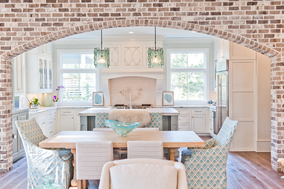 Inspiration for a large coastal u-shaped dark wood floor eat-in kitchen remodel in Jacksonville with a farmhouse sink, beaded inset cabinets, white cabinets, marble countertops, white backsplash, paneled appliances and an island