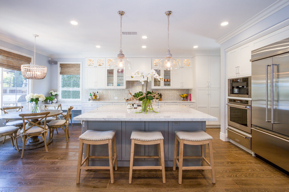 Große Klassische Wohnküche mit Schrankfronten im Shaker-Stil, weißen Schränken, Küchengeräten aus Edelstahl, braunem Holzboden und Kücheninsel in Orange County