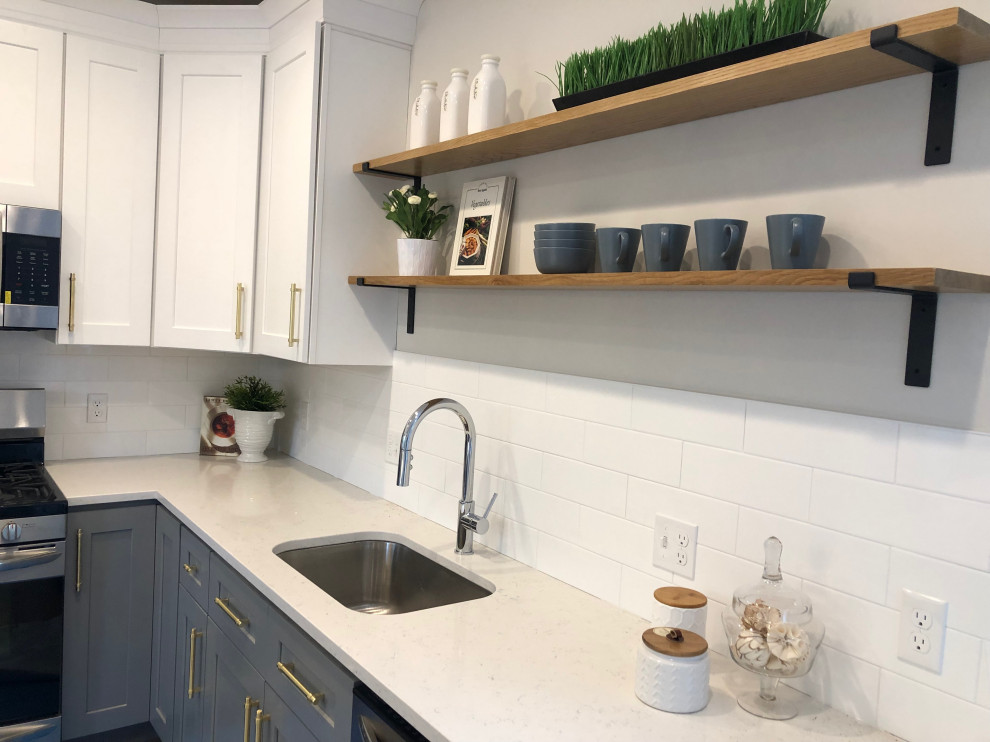 Example of a small transitional l-shaped medium tone wood floor and brown floor eat-in kitchen design in Boston with an undermount sink, recessed-panel cabinets, gray cabinets, quartz countertops, subway tile backsplash, stainless steel appliances, an island and white countertops