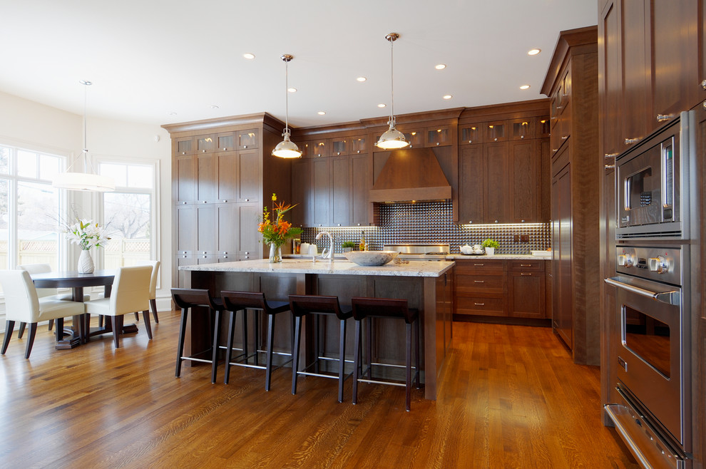 Idée de décoration pour une cuisine américaine tradition en bois foncé avec un électroménager en acier inoxydable et un placard à porte shaker.