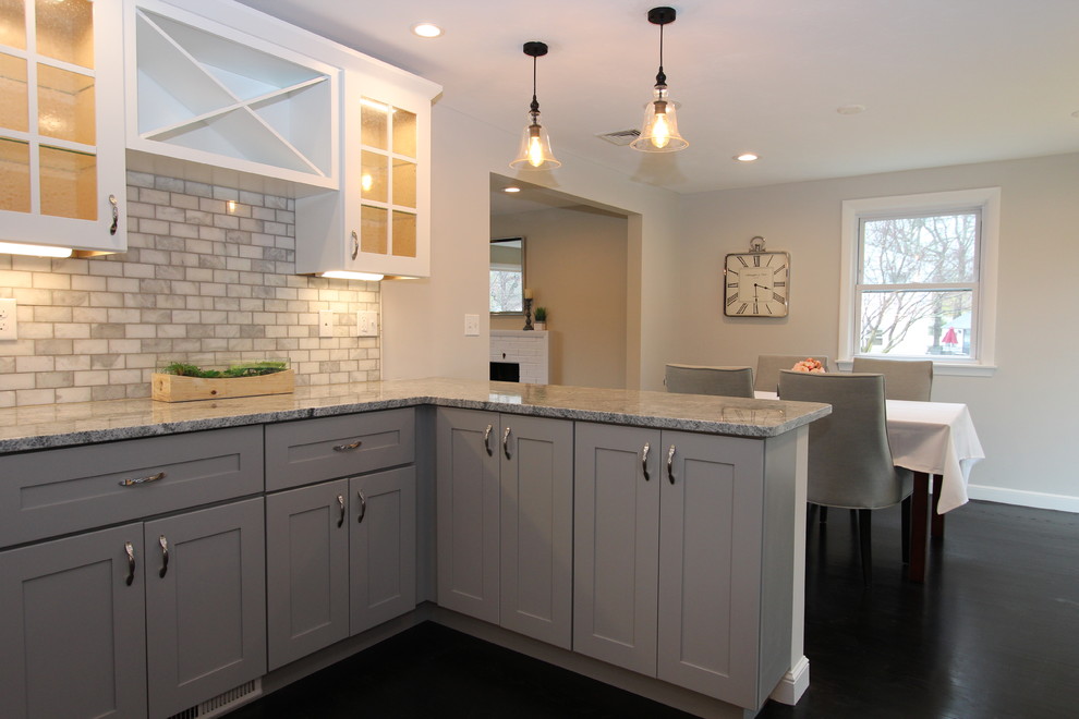 Inspiration for a mid-sized transitional dark wood floor and black floor eat-in kitchen remodel in Boston with an undermount sink, glass-front cabinets, gray cabinets, granite countertops, gray backsplash, marble backsplash, stainless steel appliances and a peninsula