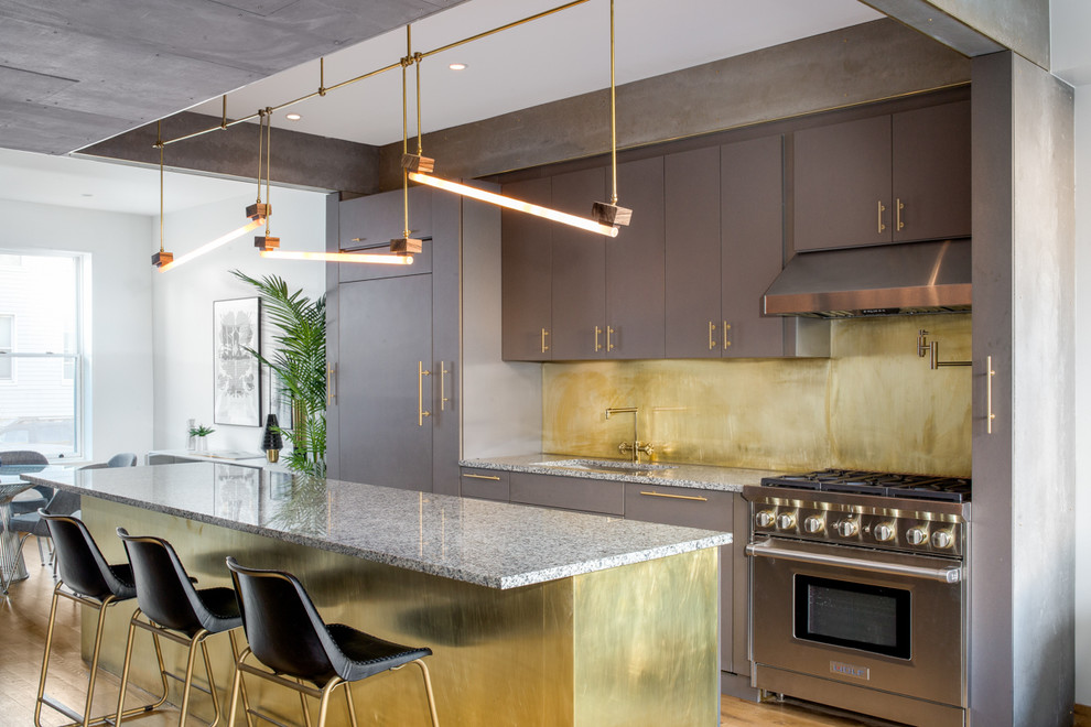 Immagine di una grande cucina design con lavello sottopiano, ante lisce, ante grigie, top in granito, paraspruzzi a effetto metallico e elettrodomestici in acciaio inossidabile