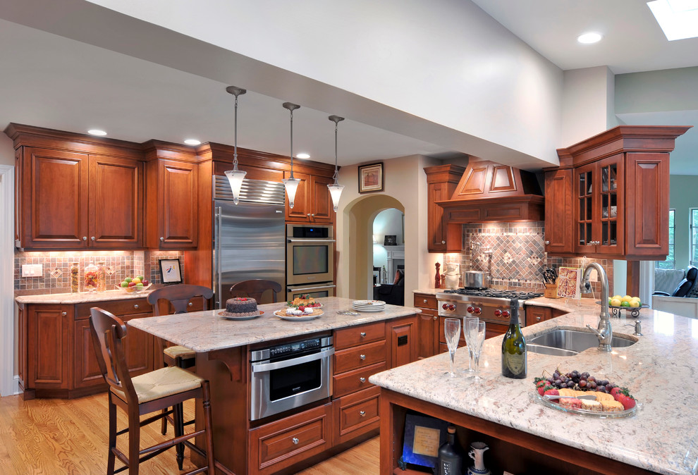 Traditional kitchen/diner in New York with a submerged sink, raised-panel cabinets, medium wood cabinets, stainless steel appliances and light hardwood flooring.