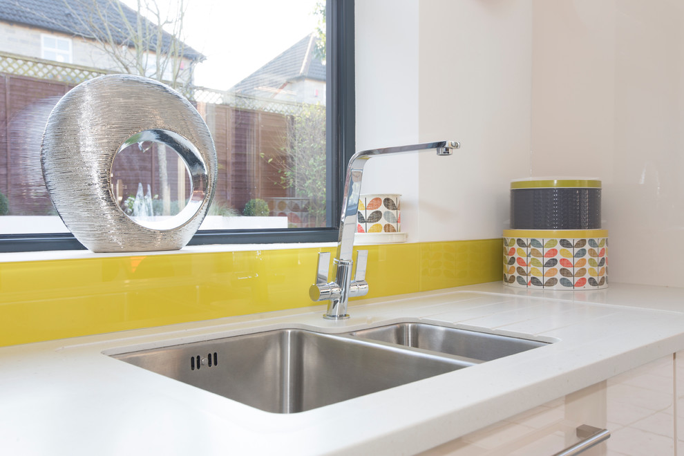 Example of a mid-sized trendy l-shaped ceramic tile eat-in kitchen design in Other with an undermount sink, flat-panel cabinets, dark wood cabinets, solid surface countertops, yellow backsplash, glass sheet backsplash, stainless steel appliances and an island