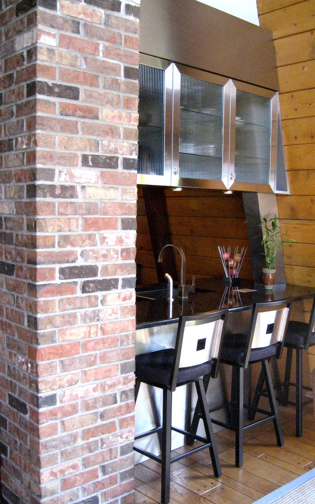 Cette image montre une petite cuisine américaine parallèle design en inox avec un évier encastré, un placard avec porte à panneau encastré, un plan de travail en granite, une crédence en carreau de verre, un électroménager en acier inoxydable, une crédence bleue et un sol en ardoise.