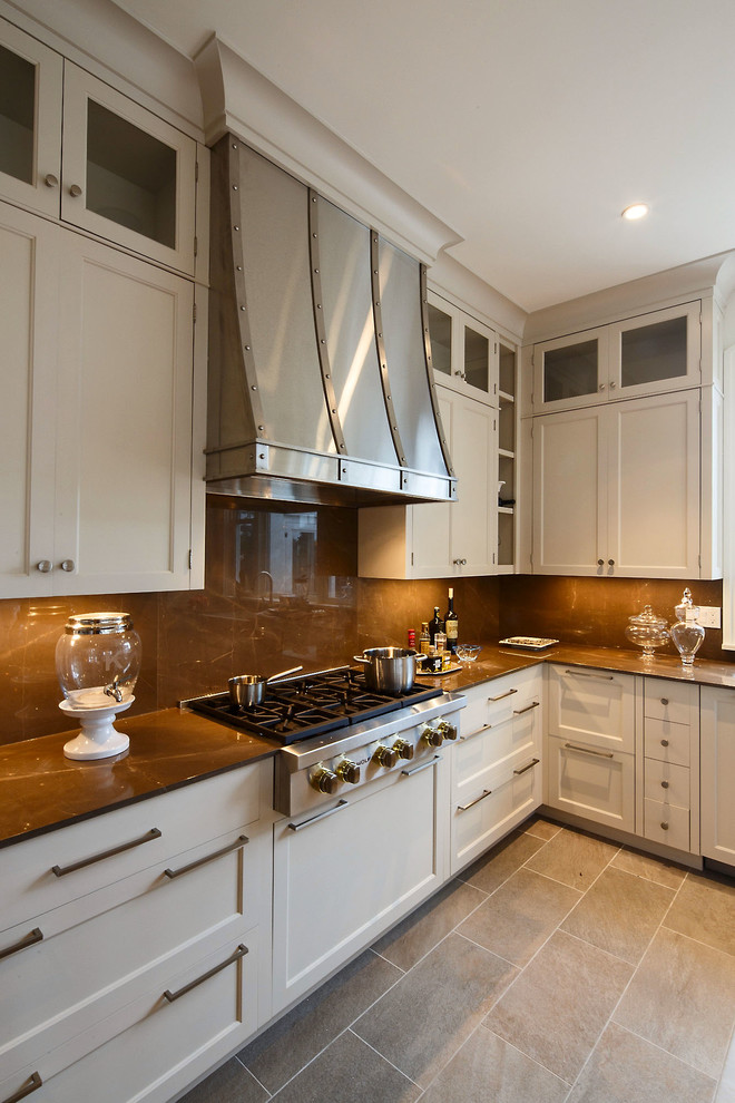 This is an example of an expansive traditional galley kitchen/diner in Boston with recessed-panel cabinets, white cabinets, marble worktops, beige splashback, stainless steel appliances, ceramic flooring and an island.