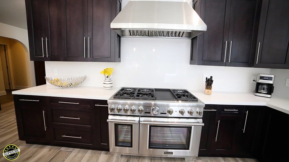 Bild på ett mellanstort funkis vit vitt kök, med en rustik diskho, skåp i shakerstil, skåp i mörkt trä, bänkskiva i kvarts, rostfria vitvaror, ljust trägolv och en köksö
